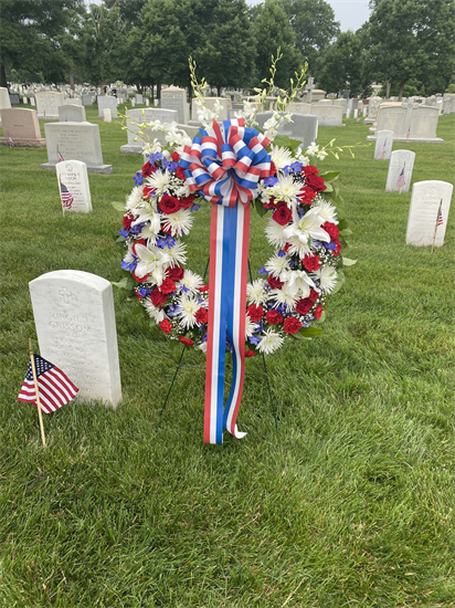 photo of a red, white, and blue wreath next to a white grave stone