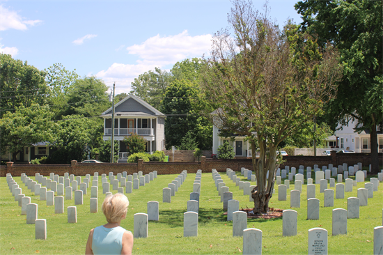 Rep. Ross standing in front of rows of white headstones, looking out onto the cemetrey